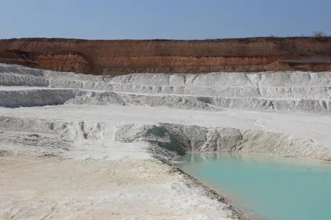Clay mining. Beautiful background of white clay. Blue water. Stock Photos