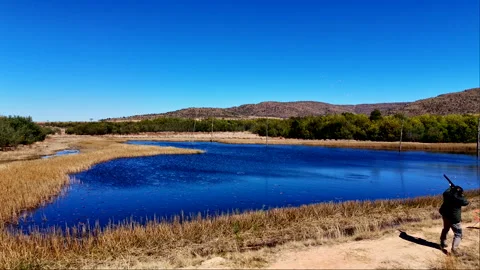 Clay pigeon explodes over dam in slomo as shooter accurately shoots Stock Footage 315092972