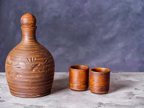 Clay pitcher and two ceramic shot glasses on a rustic background Stock Photos