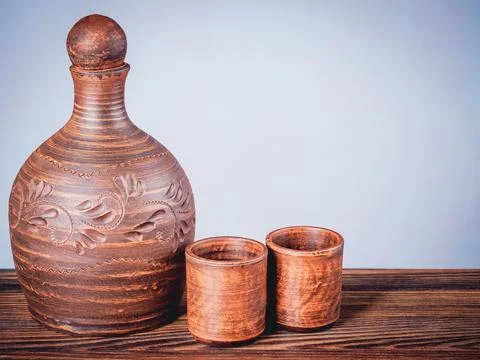 Clay pitcher and two stacks on a wooden board in still life style Stock Photos