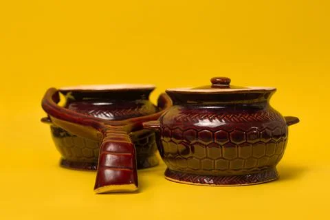 A clay pot and a handle for baking in the oven on a yellow background Photos