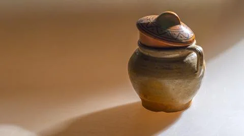 A clay pot in deep shadows on a uniform yellow background. Vintage clay pot for Stock Photos