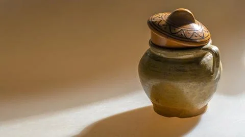 A clay pot in deep shadows on a uniform yellow background. Vintage clay pot f Stock Photos