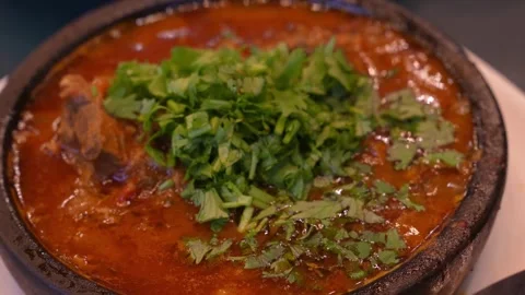 Clay pot holding steaming dish garnished with cilantro 库存影片 283758218