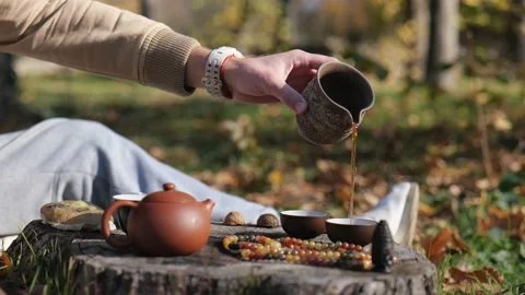From a clay pot a man pours tea into a bowl. traditional Chinese tea ceremony Видео 229859321