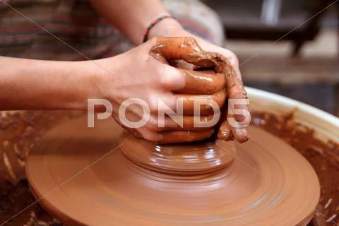 Clay potter hands closeup working on wheel handcrafts Stock Photos
