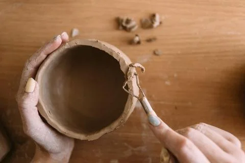 Clay potter's hands carve a pattern on the bowl. View from above. Ceramics an Stock Photos