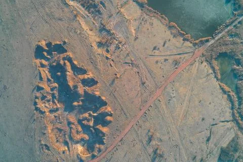 Clay quarry pit and red dirt road next to water, industrial excavation texture Stock Photos