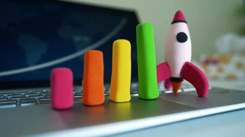 Clay Rocket and Bar Graph on Laptop Keyboard, Colorful clay rocket and bar .. Видео 304881662