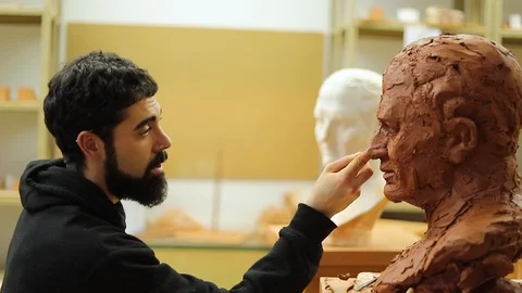 Clay sculptor making a clay bust in an art studio Stock Footage 124981180