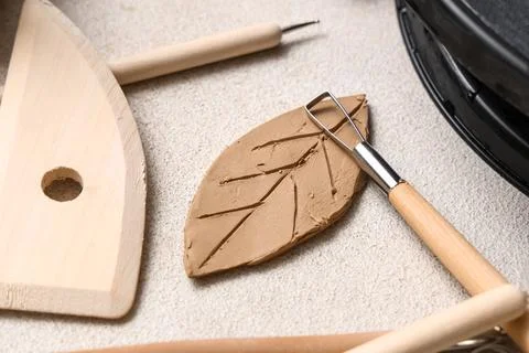 Clay in shape of leaf, loop tool and wooden rib on white grunge background, c Stock Photos