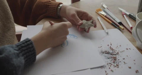 Clay star held while drawing with a red pencil on paper. Art project in progress Stock Footage 301617107