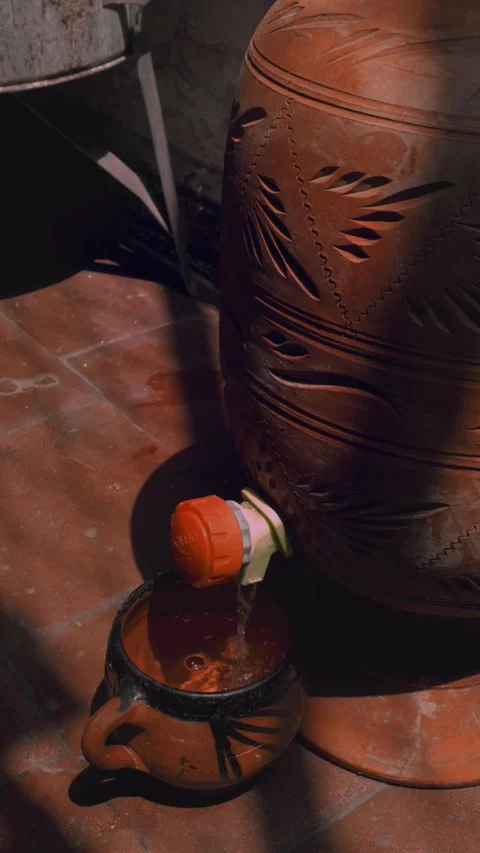 Clay Water Dispenser Pouring Into Rustic Mug Stock Footage 299576252