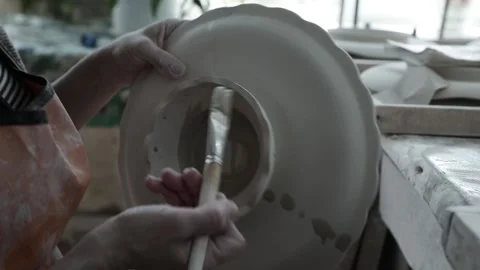 Clay workshop. Women's hands clean the roughness of the vase with a brush. Video stock 130526361