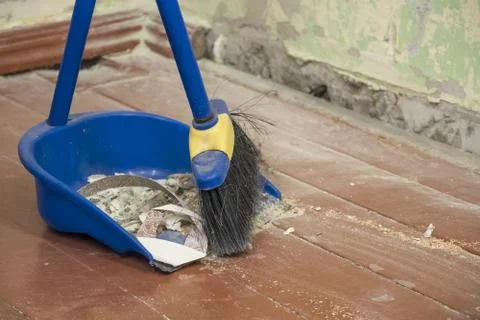 Clean up after repairs. Sweep up construction debris with a brush in a dustpa 스톡 사진