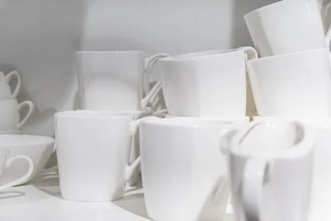 Clean and Empty drinking white ceramic cups mugs in the kitchen cabinet Stock Photos