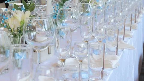 Clean and empty sets of four glasses stand next to plates and textile napkins on Stock Photos