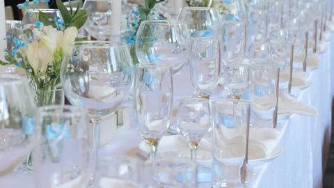 Clean and empty sets of four glasses stand next to plates and textile napkins on Stock Photos