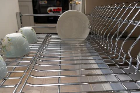 A clean and organized kitchen setup featuring a chrome dish rack with plates  Fotos Stock