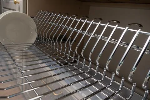 A clean and organized kitchen setup featuring a chrome dish rack with plates  Stock Photos