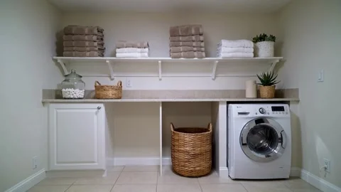 Clean and organized laundry room interior with a washing machine, wicker basket, Stock-Footage 335786252
