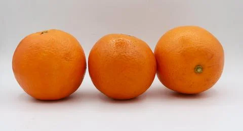 Clean arrangement of three oranges aligned on a seamless studio background. Stock Photos