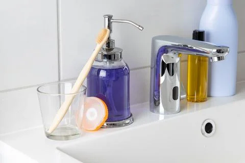 A clean bathroom sink setup features a bamboo toothbrush resting in a glass n 스톡 사진
