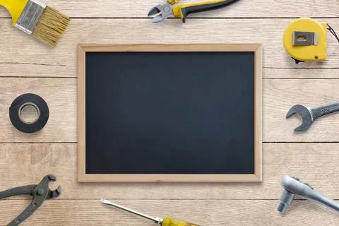 Clean chalkboard surrounded by tools: brush, pliers, screwdriver, tape Foto stock