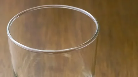 Clean clear filtered water being poured into drinking glass against dark wood Stock Footage 61531426
