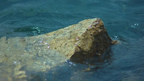 Clean Clear Water Lapping Against a Submerged Rock Stock Footage 92539246