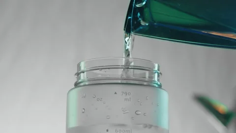 Clean clear water is poured from filter into sports bottle in kitchen. Preparing Stock Footage 230940202