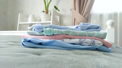 Clean colored clothes on the bed in a bedroom, soft focus background Stock Footage 239169862