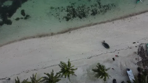 A clean deserted ocean shore with an inflatable boat on white sand near warm Stock Footage 233229382