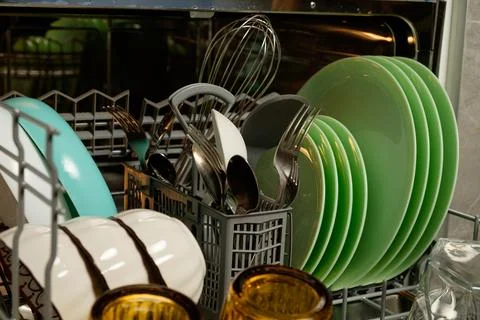 Clean dishes and silverware drying in a modern kitchen dishwasher after a meal Stock Photos