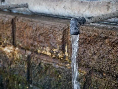 Clean drinking water flows continuously from the tap of a natural source. Lack o Stock Photos