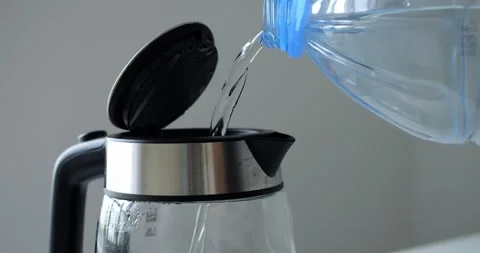 Clean drinking water streaming from plastic bottle into transparent electric Stock Footage 316757751