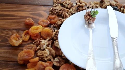 Clean empty plate and Nuts, dried apricots and prunes on a wooden table. Stock Footage 303018990