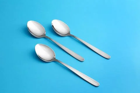 Clean empty table spoons on blue background Stock Photos