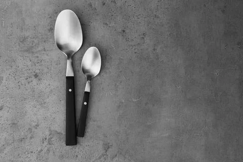 Clean empty table spoons on grey background, top view. Space for text Stock Photos