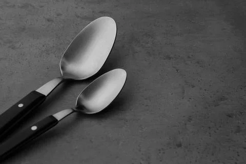 Clean empty table spoons on grey background, space for text Stock Photos