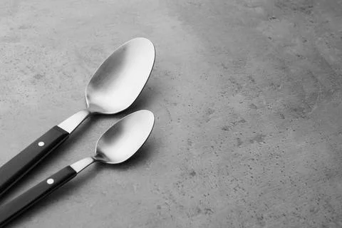 Clean empty table spoons on grey background, space for text Stock Photos