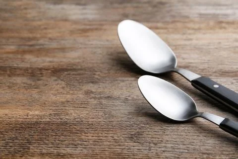 Clean empty table spoons on wooden background, space for text Stock Photos