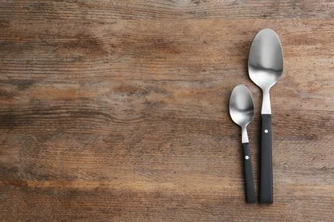 Clean empty table spoons on wooden background, top view. Space for text Stock Photos