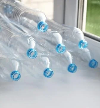 Clean empty used plastic water bottles on table - recycling and food storage  Stock Photos