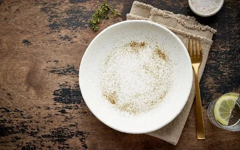 Clean empty white ceramic plate, fork and knife on brown dark old table, copy Stock Photos