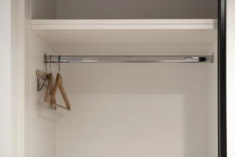 Clean empty white wardrobe interior with modern wooden hangers on a shining.. Stock Photos