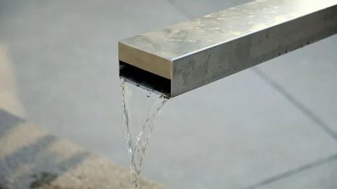 Clean fresh water flows from a modern stainless steel and concrete fountain. 库存影片 115824932