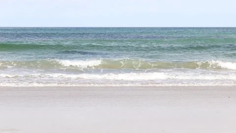 Clean fresh white tipped waves roll on to the golden sand Stock Footage 132050156
