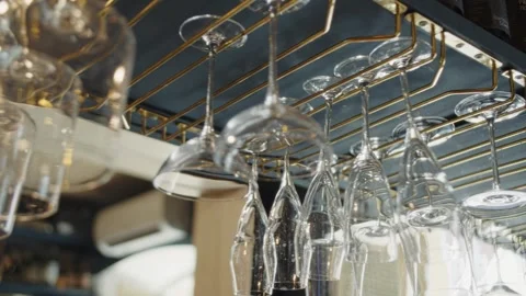 Clean glasses hang upside down over the bar counter in a restaurant Stock Footage 302499743