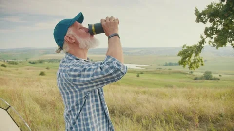 Clean Hydration, Preventive Wellness. Senior Man Drinks Water in Nature Stock Footage 306888909